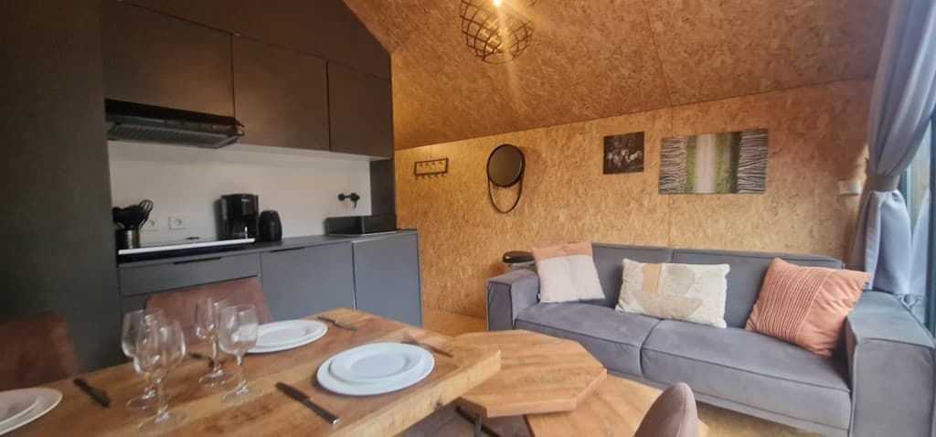 Moderne woonkamer met een bank, eettafel, kitchenette en decoratieve muur met foto's en een spiegel