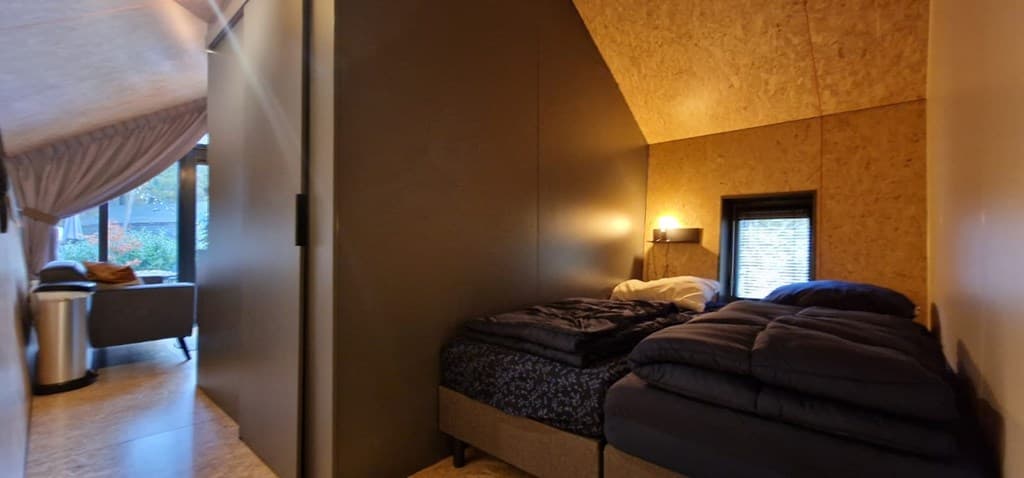 Slaapkamer met twee eenpersoonsbedden en sfeervolle verlichting naast een wand in een houten interieur