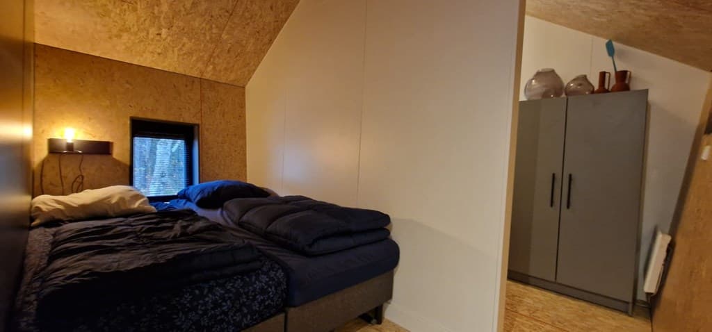 Slaapkamer met twee eenpersoonsbedden, een raam en een kast tegen de muur