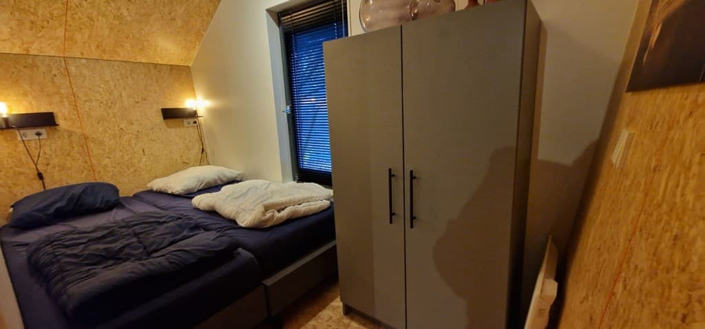 Sfeervolle slaapkamer met twee bedden, een kast en houten muren in EuroParcs Ruinen.