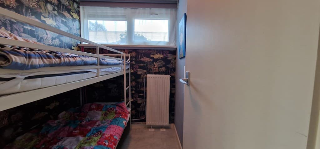 Slaapkamer met stapelbed, radiator en kleurrijke muurbekleding met dierenmotieven
