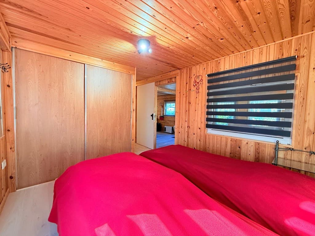 Slaapkamer met twee losse bedden, houten wandafwerking en gordijnen met verduistering.