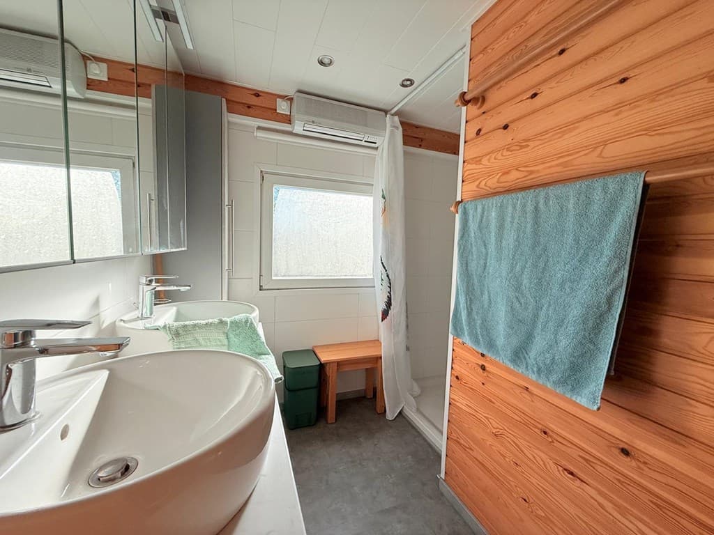 Moderne badkamer met houten accenten, wastafel, spiegel, handdoek en een raam voor natuurlijk licht