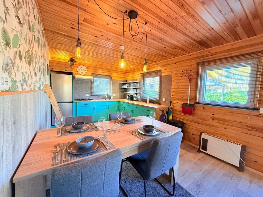 Houtenruimte met keuken en eettafel, groenblauwe kasten, houten wanddecoratie en grote ramen voor natuurlijk licht