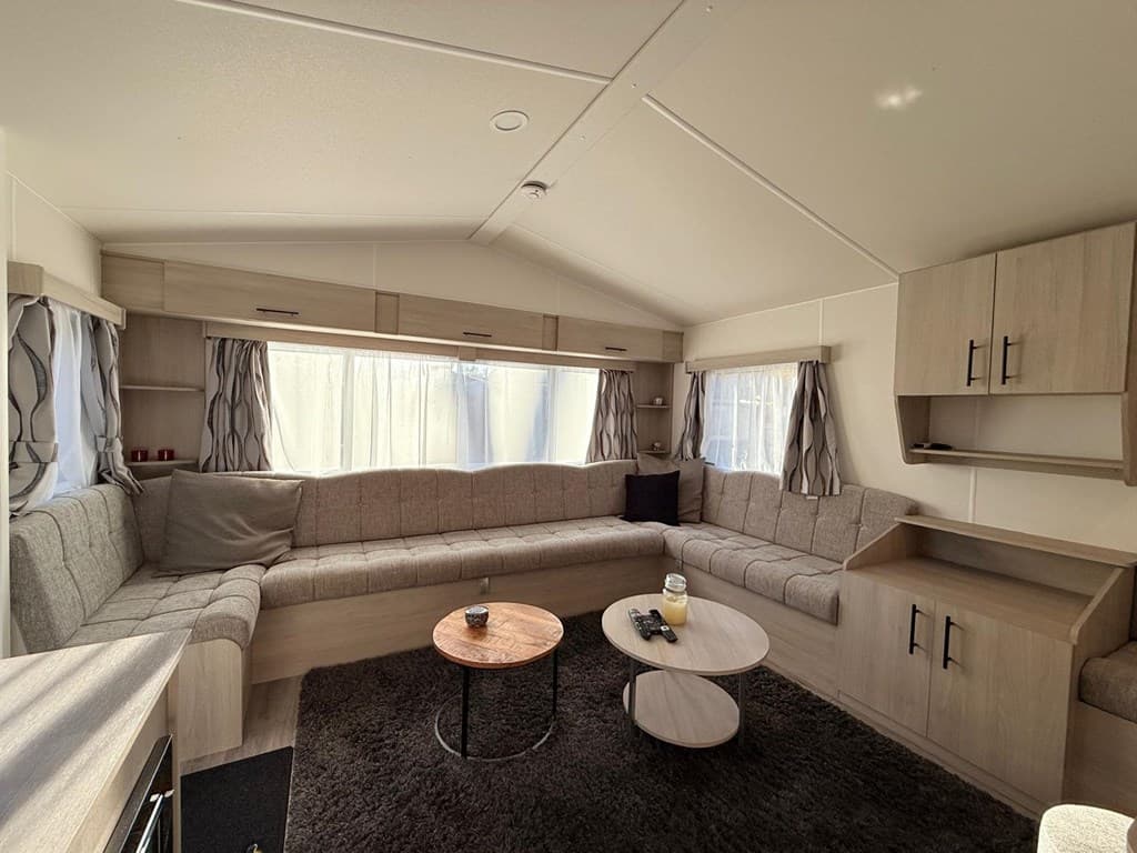 Lichte woonkamer met een grote U-vormige zithoek, twee ronde tafels en ramen voor veel natuurlijk licht