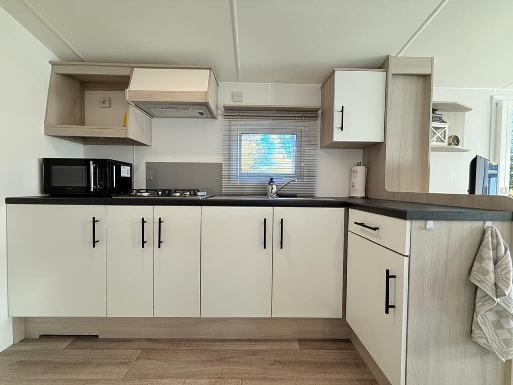 Moderne keuken met lichte kasten, gasfornuis, afzuigkap, magnetron en spoelbak bij Camping Zavelbos in Maaseik
