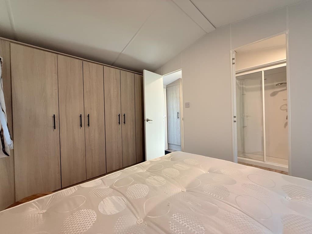 Slaapkamer met een groot bed, kledingkast en toegang tot een badkamer met douche.
