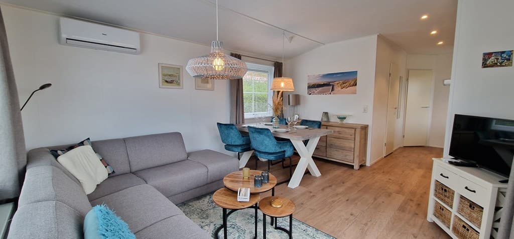 Moderne woonkamer met zithoek, eettafel en tv-kast, lichte kleuren en natuurlijke materialen.