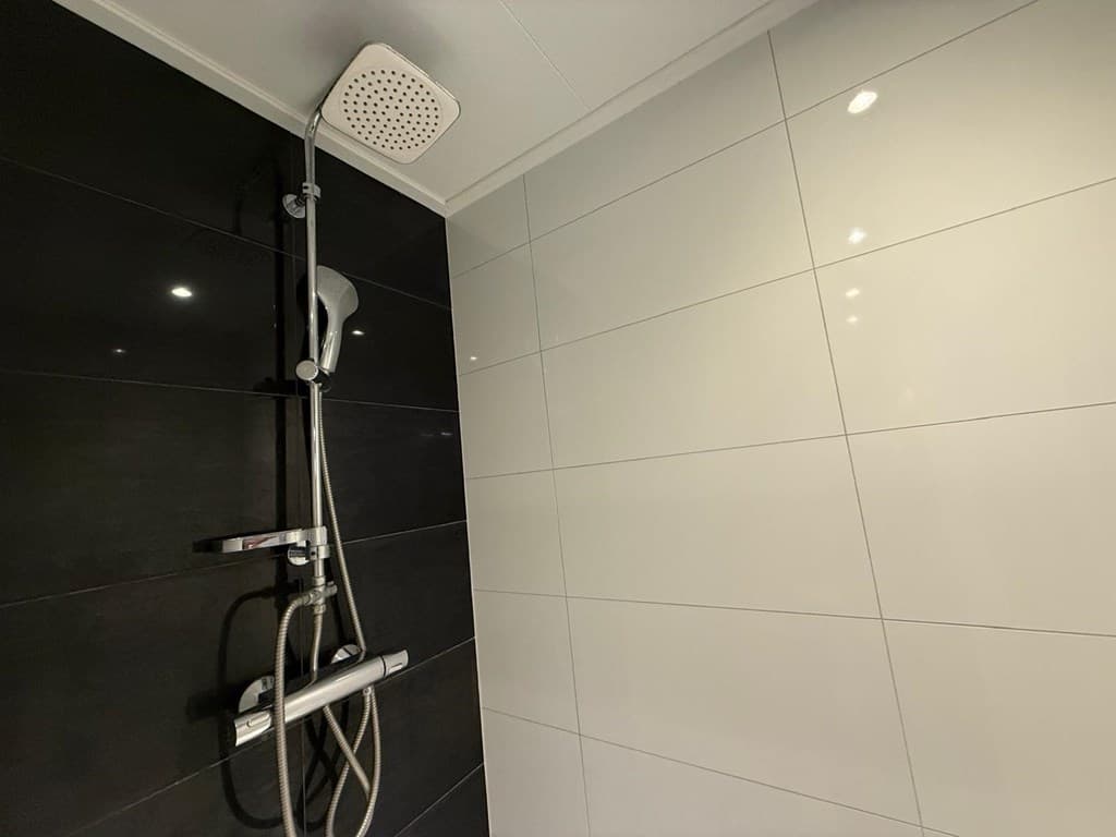 Douche met een moderne regendouche en tegelwanden in zwart en wit