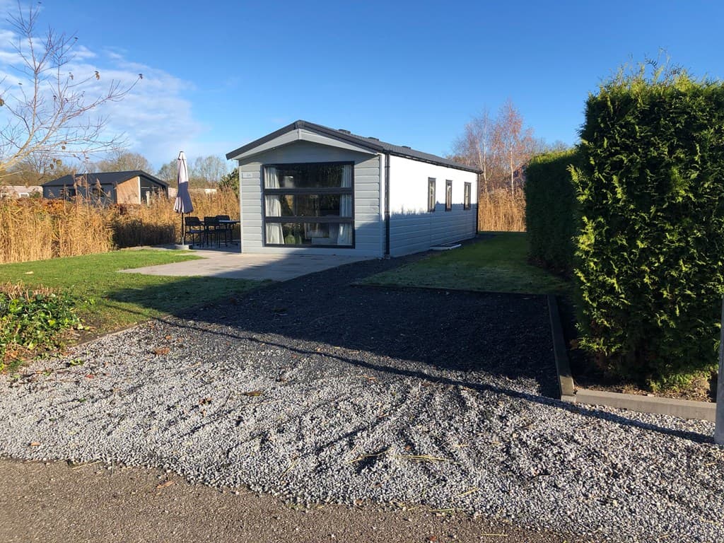 Vakantiewoning met moderne uitstraling, grote ramen en aangelegde tuin met gras en gravelpad