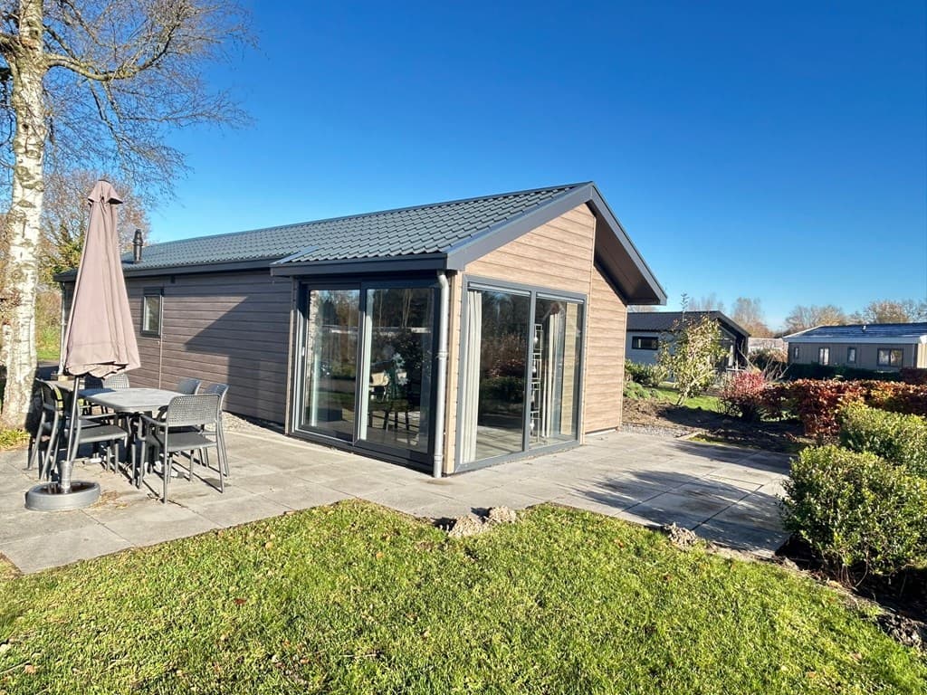 Moderne vakantiewoning met grote glazen pui, terras met tuinmeubelen en groene omgeving bij EuroParcs Zuiderzee