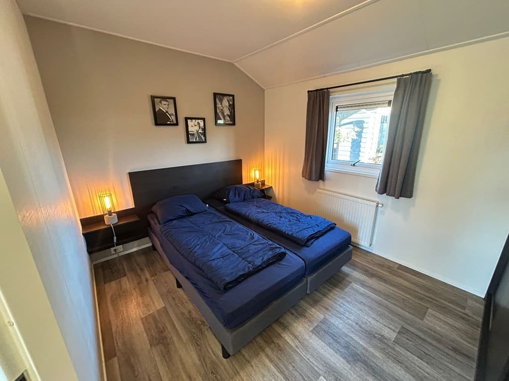 Slaapkamer met twee eenpersoonsbedden, lampen naast het bed en een raam met gordijnen.
