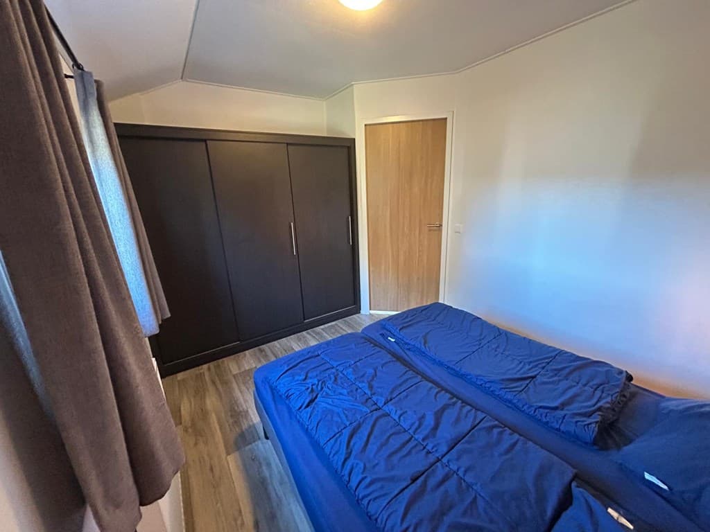 Slaapkamer met twee eenpersoonsbedden, kledingkast en raam met gordijnen.