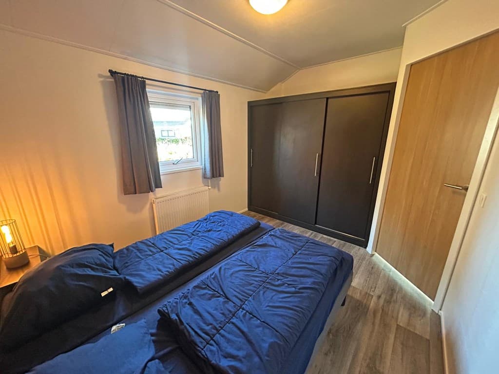 Slaapkamer met twee eenpersoonsbedden, een kastenwand en een raam met gordijnen.