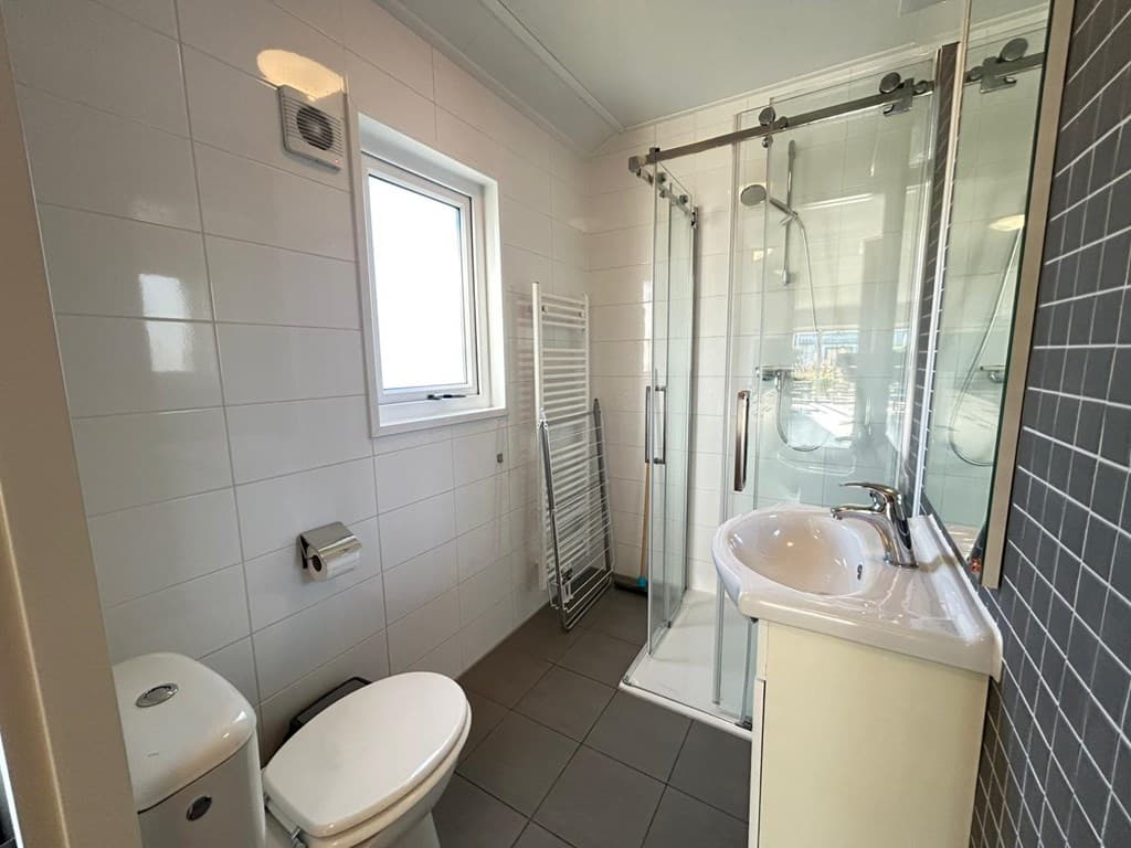 Moderne badkamer met inloopdouche, toilet, wastafel en een verwarmingselement aan de wand.