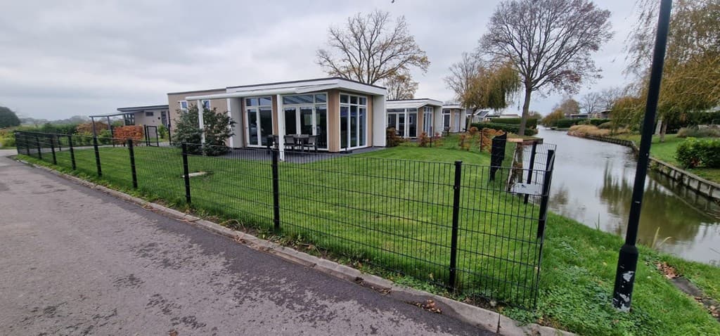 Moderne vakantiewoning met omheinde tuin en uitzicht op waterpartijen, gelegen in een groen park.