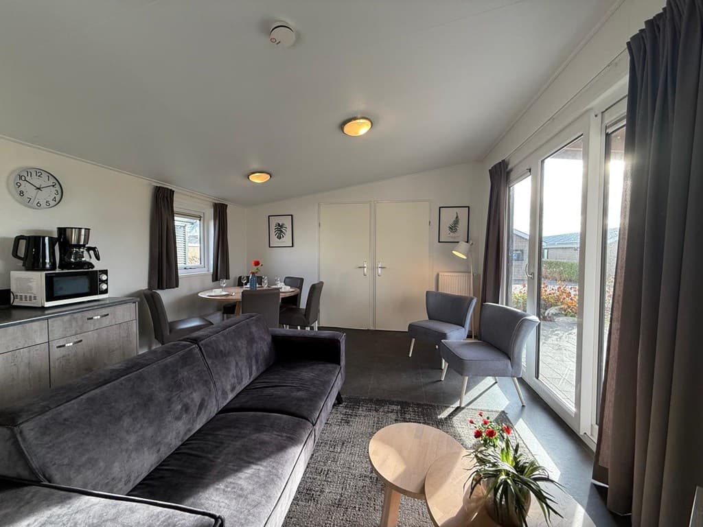 Moderne woonkamer met zithoek, eettafel, keukenapparatuur en grote ramen naar buiten