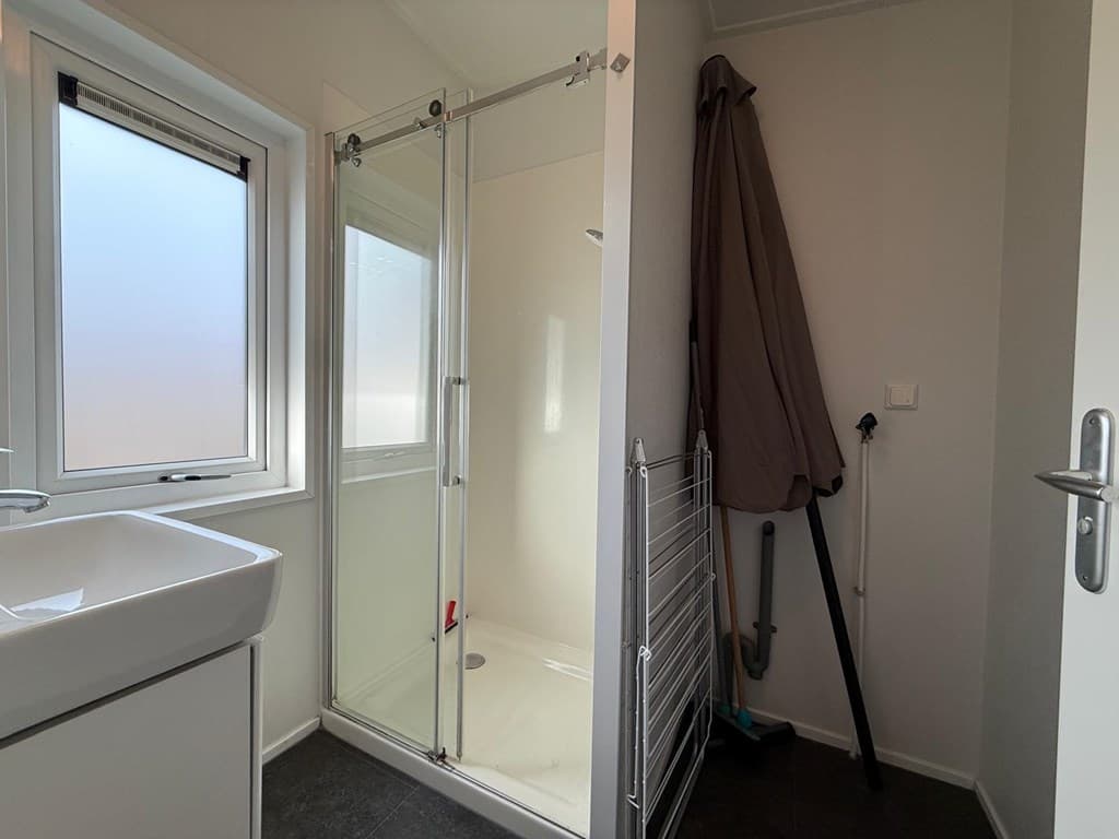 Moderne badkamer met inloopdouche, wastafel en raam voor natuurlijk licht