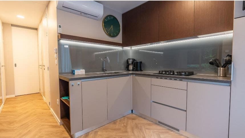 Moderne keuken met houten kasten, een inductiekookplaat, en inbouwapparatuur in een lichte ruimte met houtlook vloer.