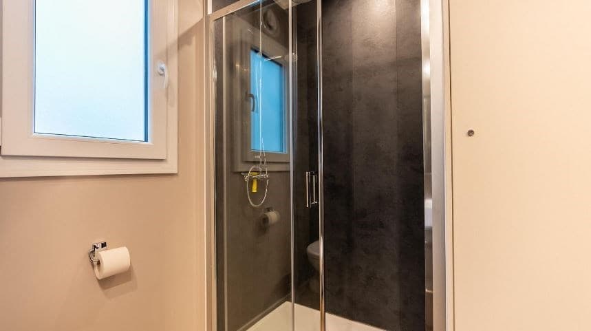 Moderne badkamer met douchecabine, toilet en raampje voor natuurlijk licht.