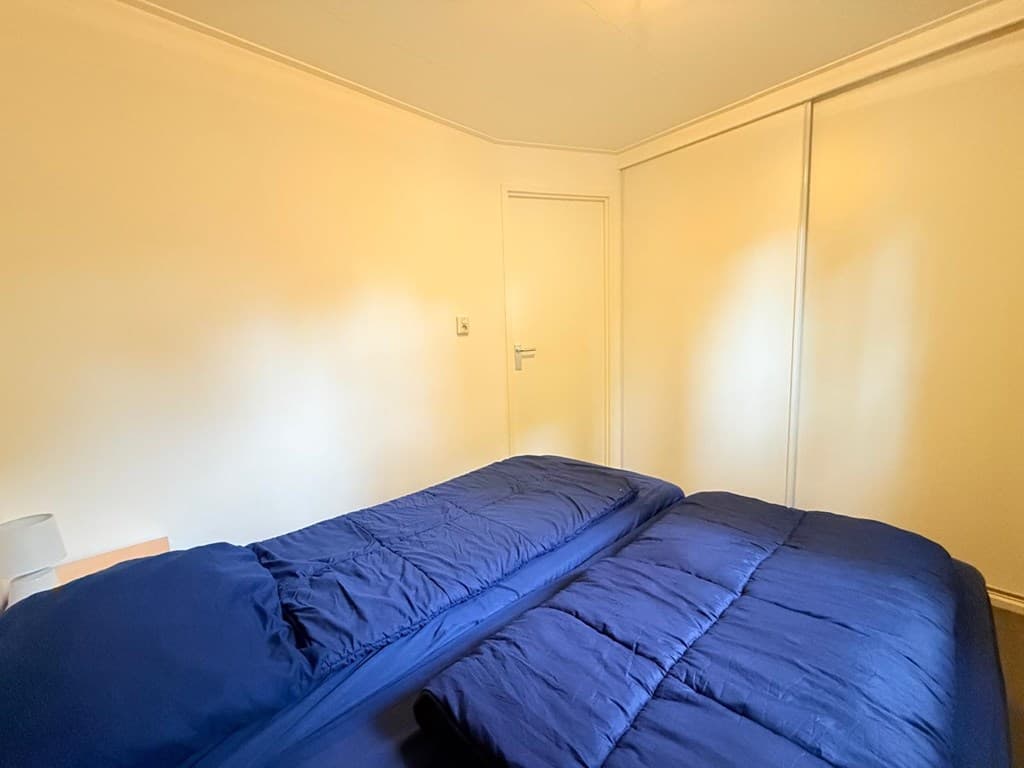 Slaapkamer met twee aparte bedden en een witte kastwand aan de rechterzijde