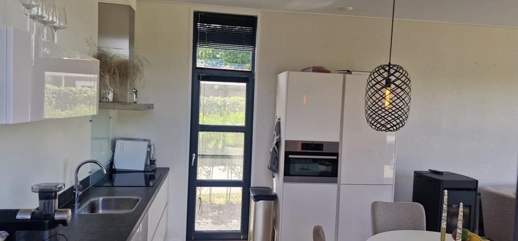 Moderne open keuken met wit meubilair, een koelkast, en een eetgedeelte met een ronde tafel en stoelen.