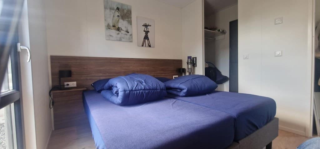 Slaapkamer met twee aparte bedden en een schilderij aan de muur, voorzien van raampartij voor natuurlijk licht.