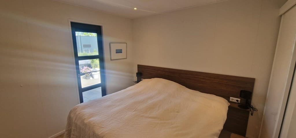 Slaapkamer met een tweepersoonsbed, wandlampen en een raam met uitzicht op buiten.