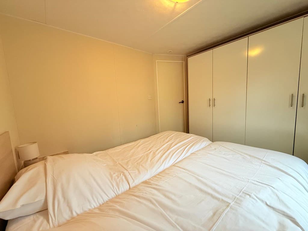 Slaapkamer met twee eenpersoonsbedden en een grote kast tegen de muur.
