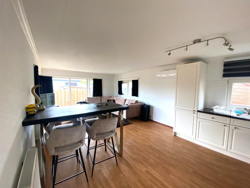 Ruime vakantiewoning met zitgedeelte, eettafel en open keuken, lichte inrichting en houten vloer
