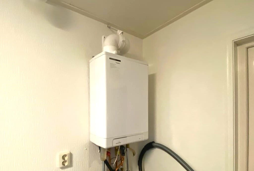 Wit wandmeubilair met een verwarmingsketel en aansluitingen in een lichte, neutrale ruimte