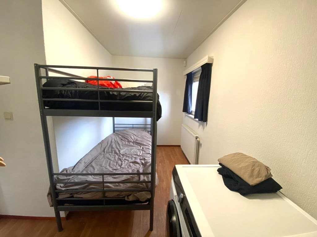 Slaapkamer met stapelbed, eenpersoonsbed en een wastafel naast de muur.