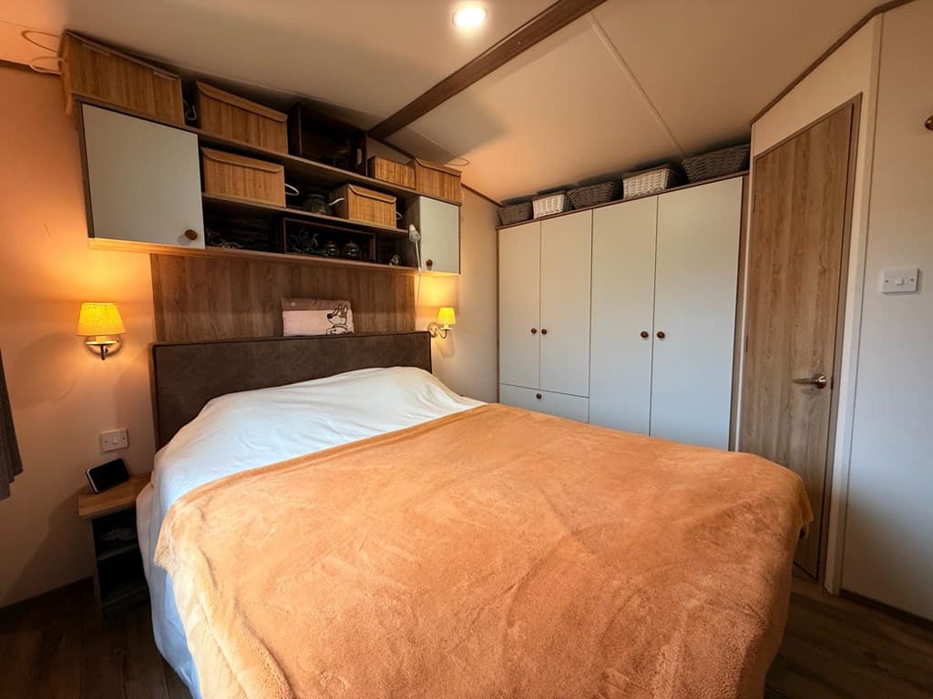 Slaapkamer met een groot bed, wandkasten en zachte verlichting in een recreatiewoning.
