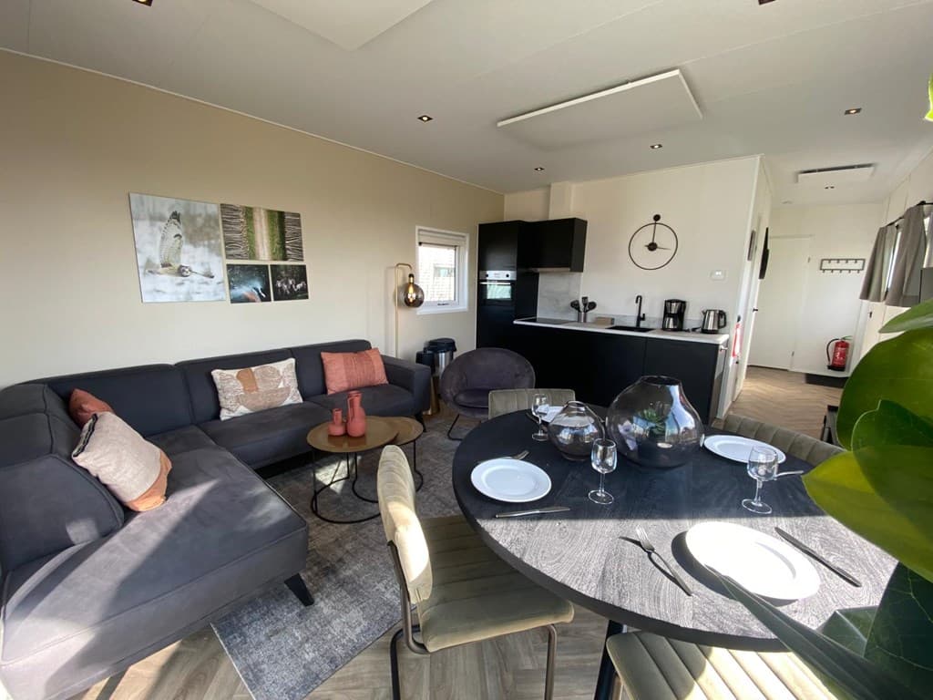 Moderne woonkamer met een zithoek, eettafel en open keuken in vakantiehuis op vakantiepark De Wiedense Meren