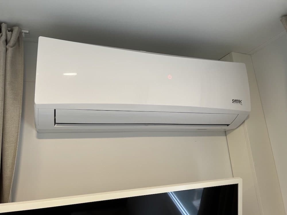 Witte wand-airco boven een televisie in een vakantiewoning.