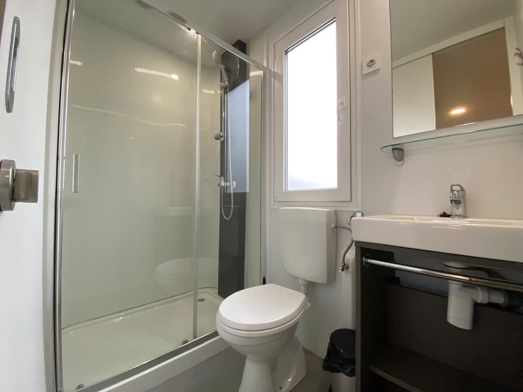 Moderne badkamer met douchecabine, toilet en wastafel, voorzien van een raam voor natuurlijke verlichting