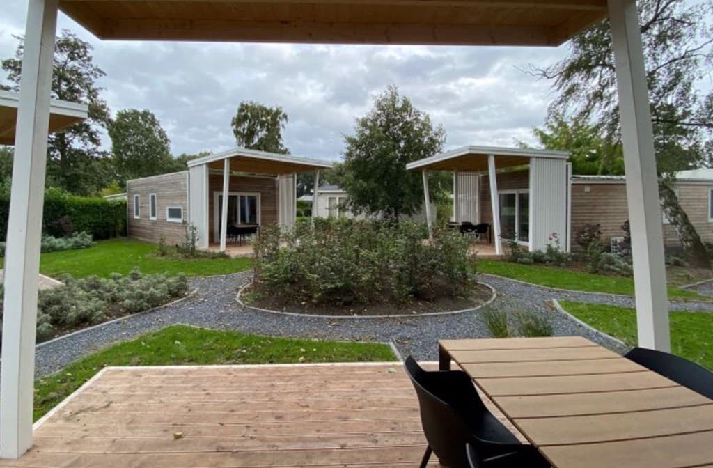 Uitzicht op een groene tuin met gravelpaden en moderne woningen met houten gevels op EuroParcs De Biesbosch