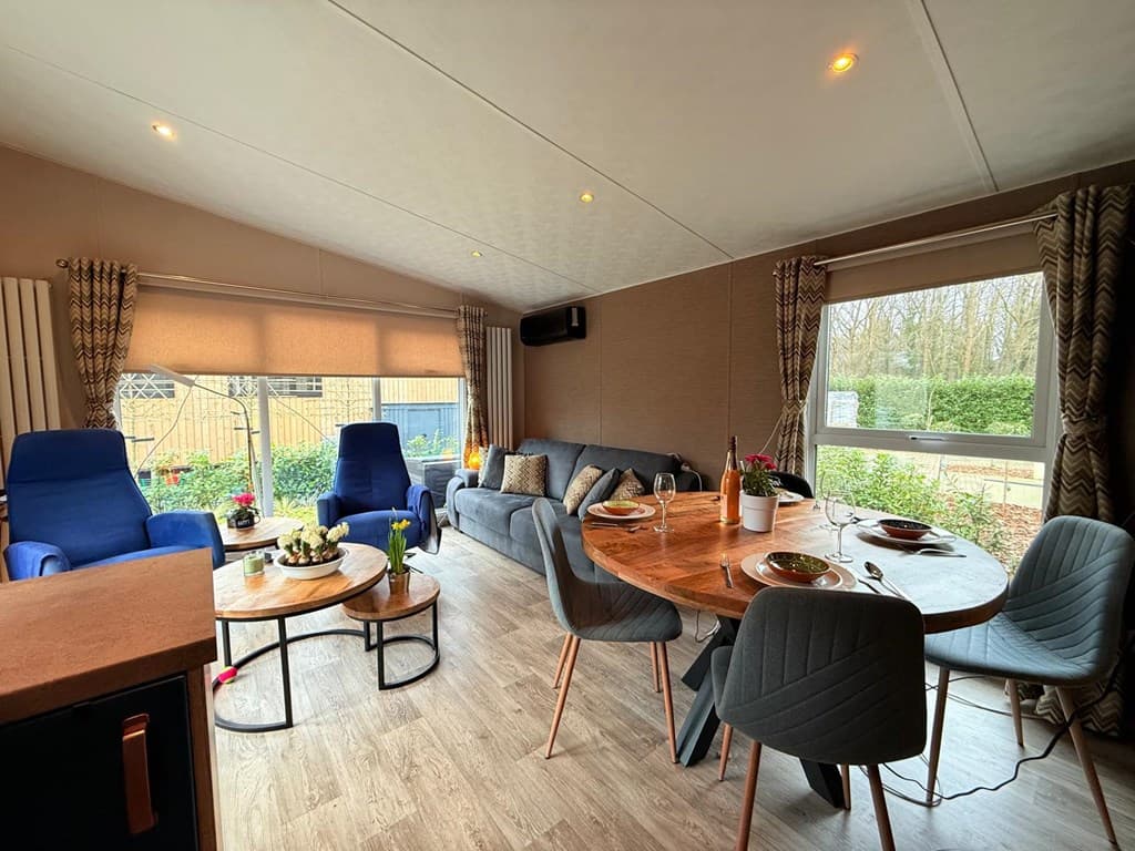 Woonruimte met banken, eetkamer met tafel en stoelen, en grote ramen met uitzicht op de tuin.