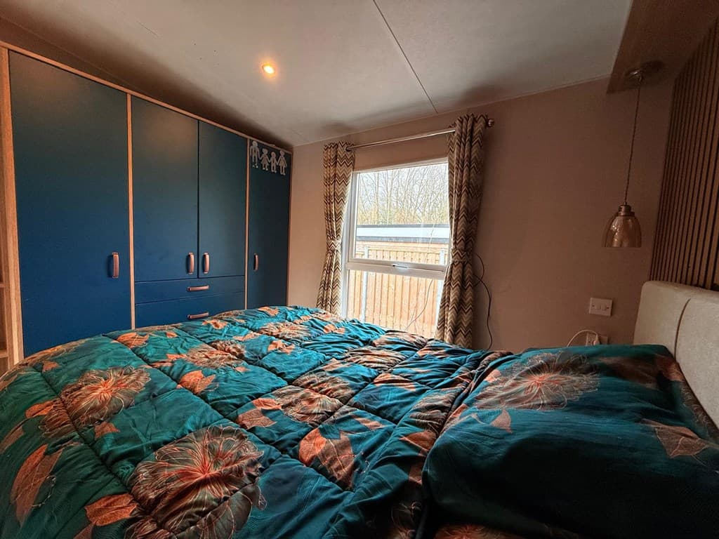 Slaapkamer met een bed, kast met blauwe deuren en een raam met gordijnen.
