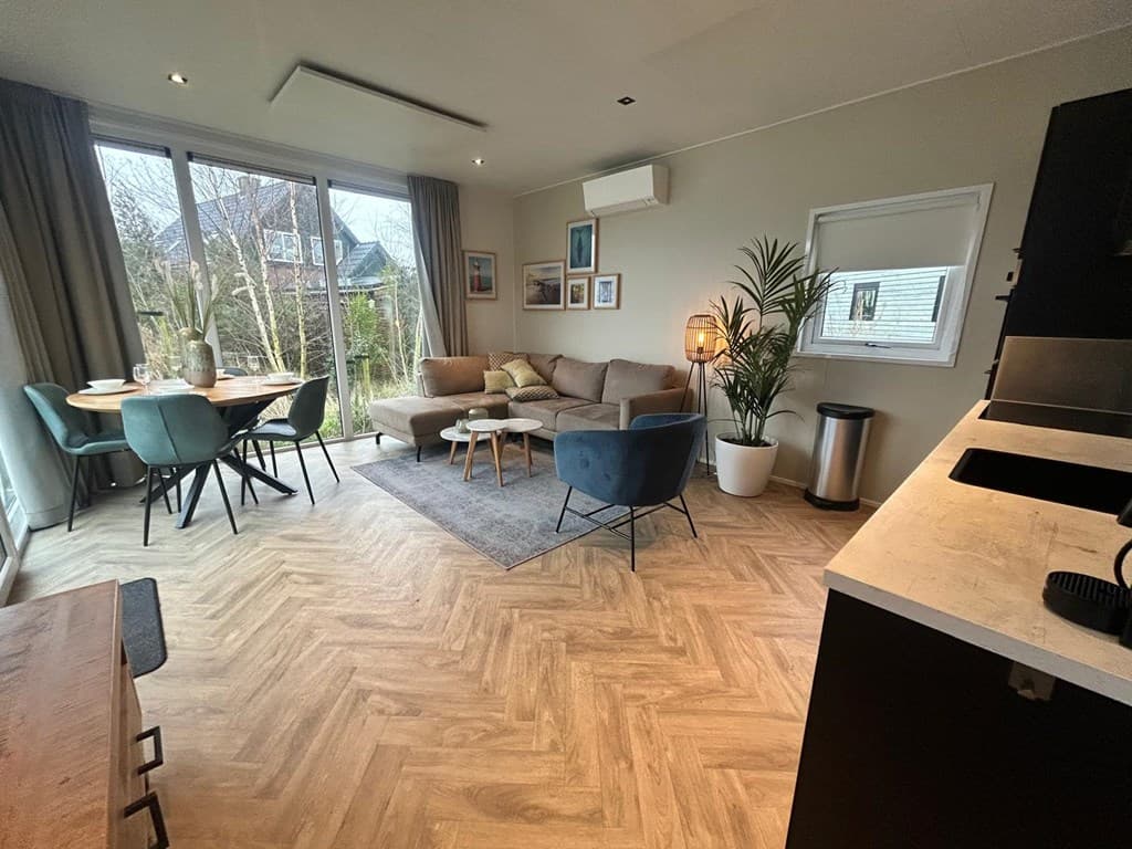 Hedendaagse woonkamer met zithoek, eettafel en grote raampartij naar de tuin
