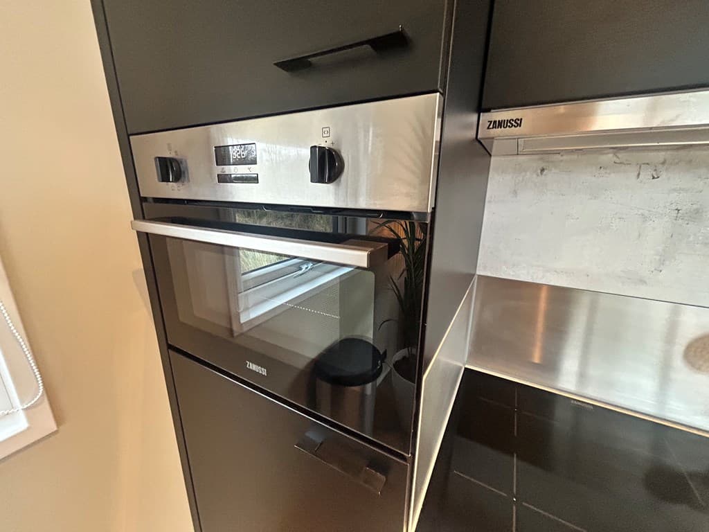 Ingebouwde ovens en magnetron in een moderne keuken met een strakke afwerking.