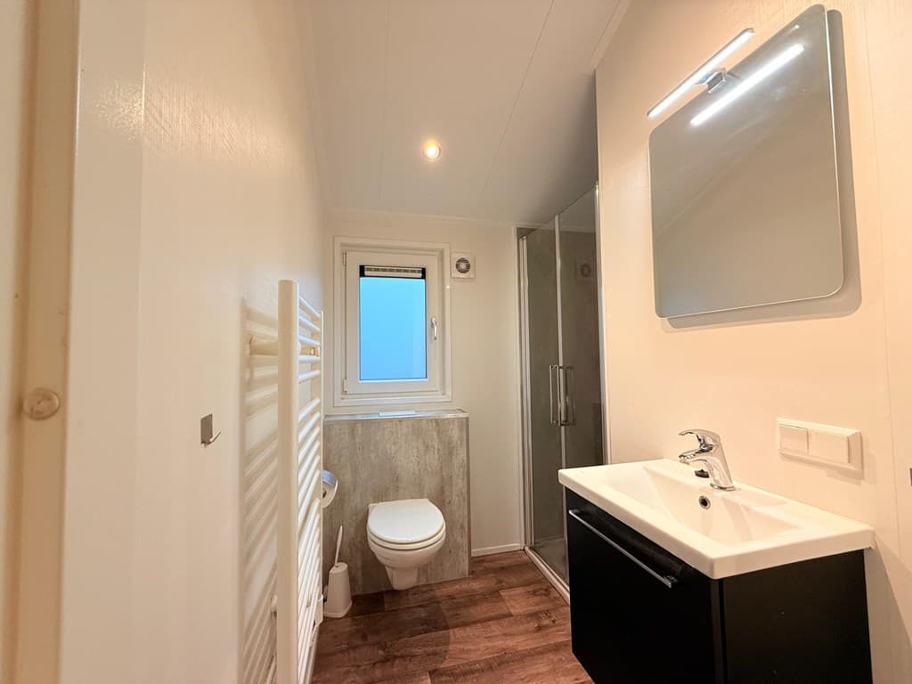 Moderne badkamer met douche, wastafel, toilet en raam voor natuurlijke lichtinval