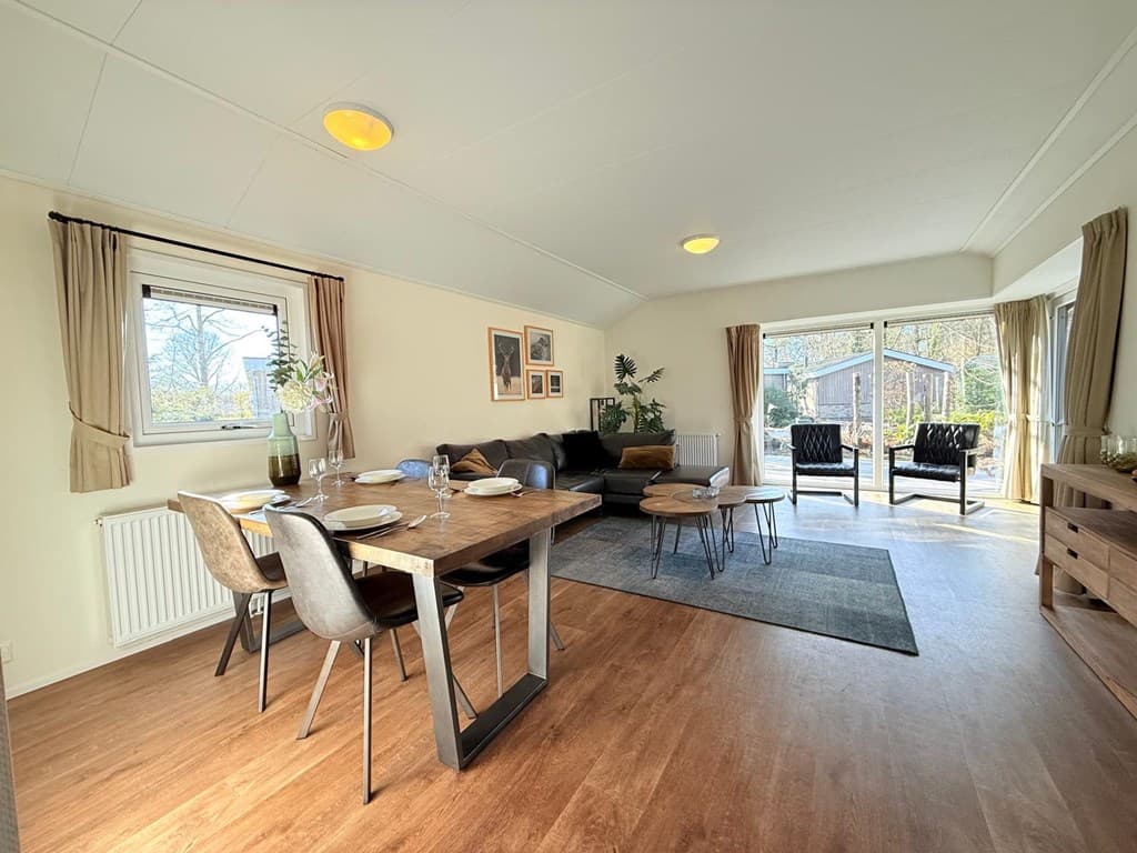 Moderne woonruimte met eettafel, zithoek en uitzicht op buiten met veel lichtinvloed en planten.