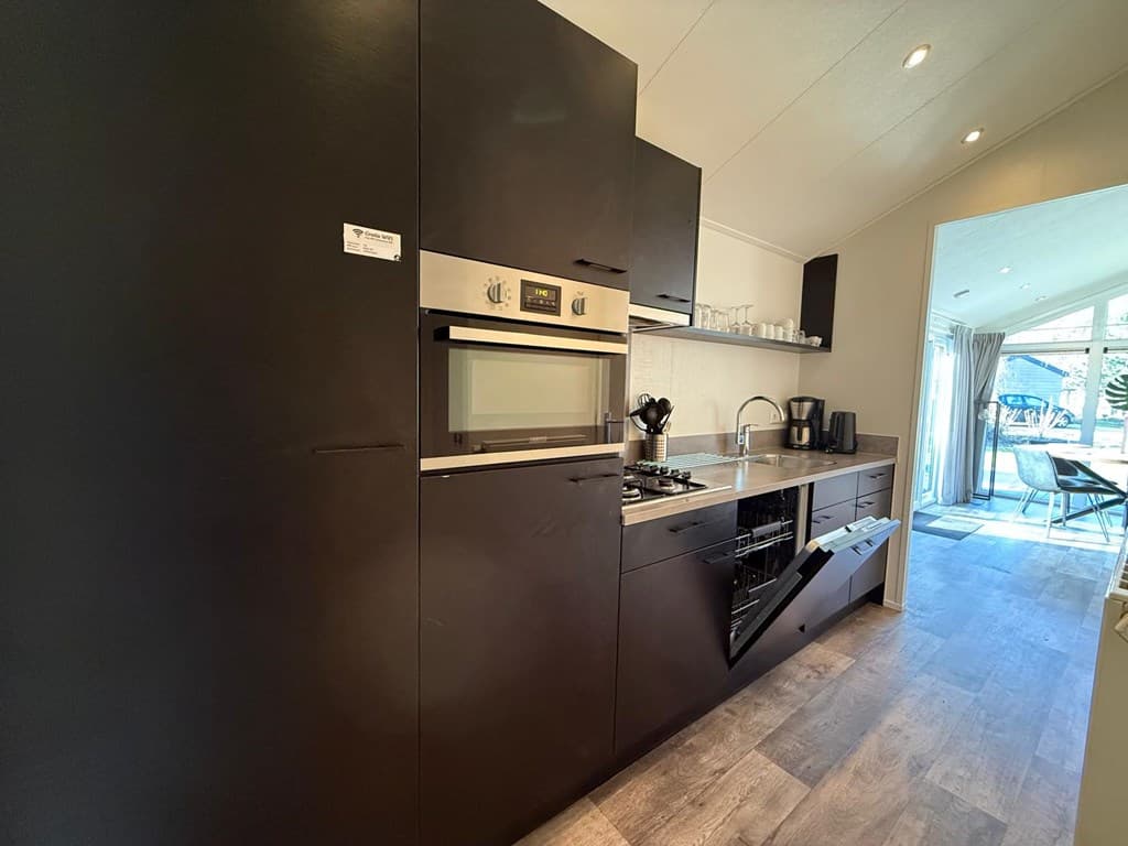 Moderne keuken met zwarte kasten, kookplaat, oven en apparatuur in EuroParcs Resort De Utrechtse Heuvelrug