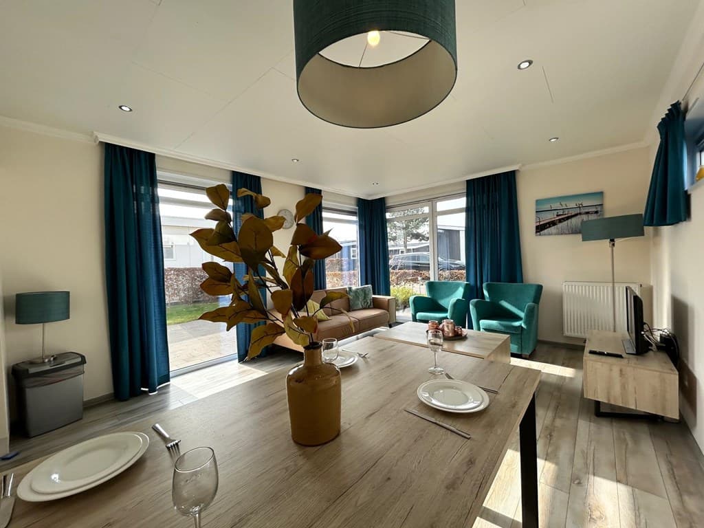 Lichte woonkamer met eettafel, zithoek en grote ramen met uitzicht op de tuin, groen en moderne decoratie.