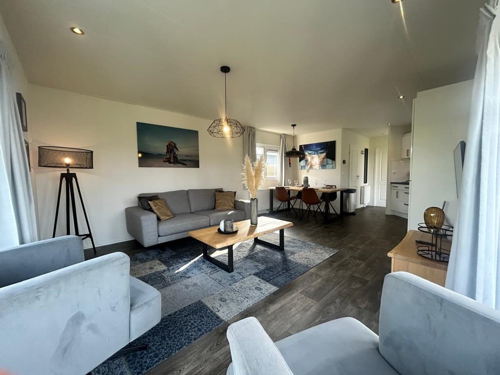 Moderne woonkamer met bank, stoelen en eettafel bij EuroParcs Bad Hulckesteijn in Nijkerk. Decoratieve elementen zichtbaar.