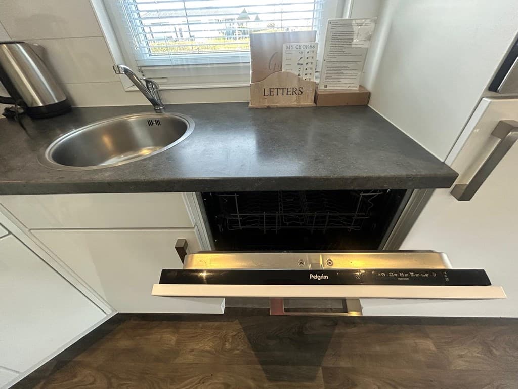 Uitzicht op een moderne keuken met een spoelbak, een afwasmachine en een opbergdoos voor brieven.