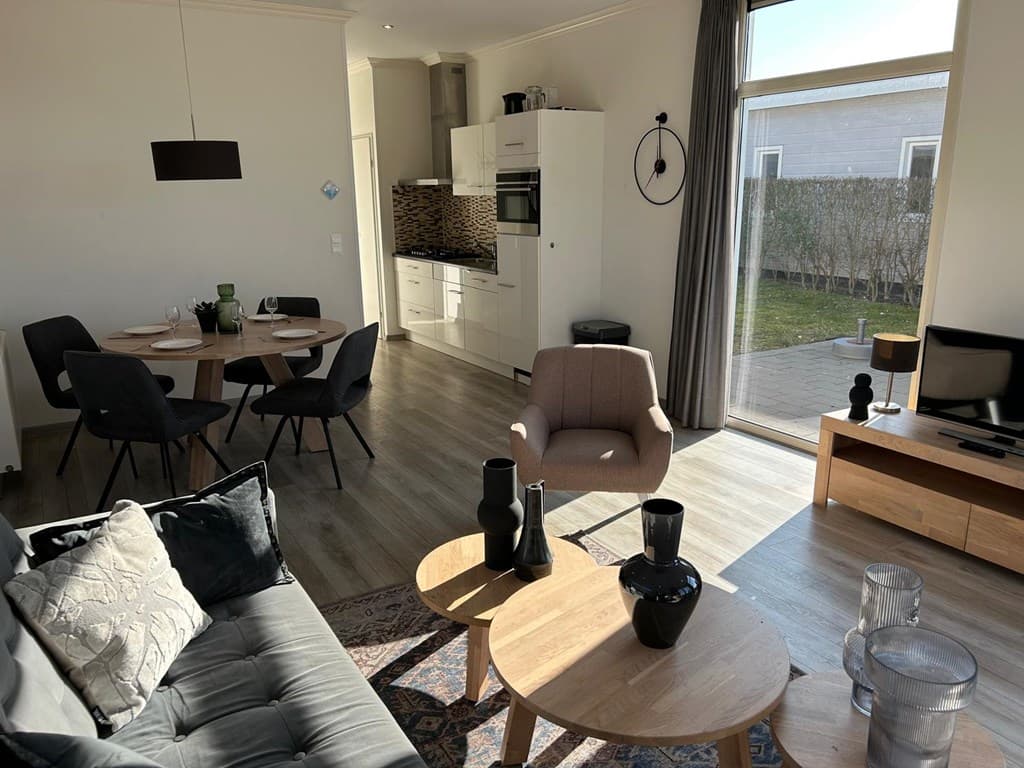 Moderne woonkamer met open keuken, eetgedeelte en toegang tot de tuin en terras.