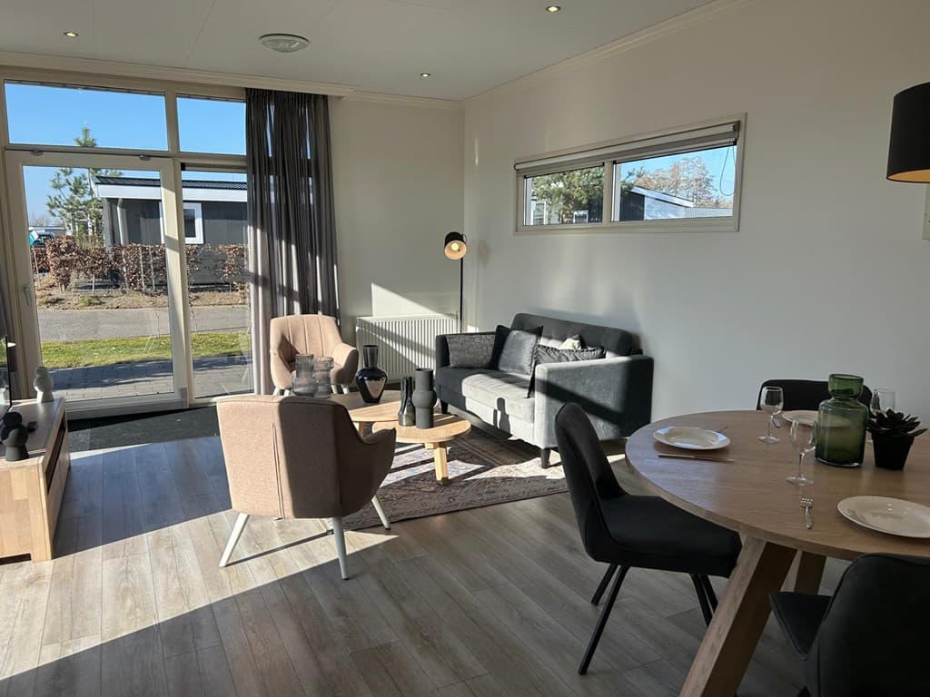 Lichte woonkamer met zithoek, eettafel en uitzicht op buitenruimte met moderne inrichting en raampartijen