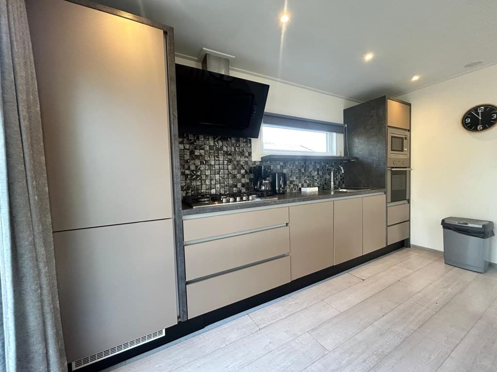 Moderne keuken met inbouwapparatuur en een dichtgelijnd wanddecor in lichte kleuren, raam met natuurlijk licht.